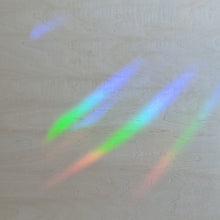 Load image into Gallery viewer, Rainbow streaks of light on a light wood background.