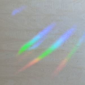 Rainbow streaks of light on a light wood background.