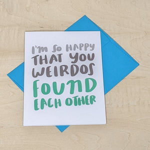 Greeting card by Craft Boner laid on a bright blue envelope Card reads "I'm so happy that you weirdos found each other" available at Coyote Supply Co, a zero waste witch store in Midtown Reno, Nevada that is BIPOC owned