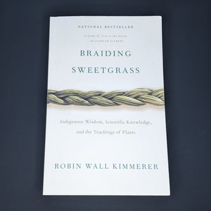 White book by Robin Wall Kimmerer features a photo of a sweetgrass braid and reads "Braiding Sweetgrass" in green serif letters available at Coyote Supply Co, a zero waste witch store in Midtown Reno, Nevada that is BIPOC owned