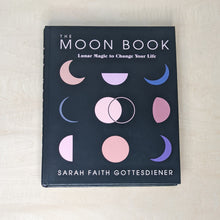 Load image into Gallery viewer, Black hardcover book by Sarah Faith Gottesdiener. Cover features a black background with colorful moon phases and reads &quot;The Moon Book&quot; in white block letters available at Coyote Supply Co, a zero waste witch store in Midtown Reno, Nevada that is BIPOC owned