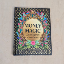 Load image into Gallery viewer, Black book cover of Money Magic by Jessie Susannah Karnatz, the Money Witch. Cover features a gold frame with the title inside it and colorful pink a blue flowers surrounding it available at Coyote Supply Co, a zero waste witch store in Midtown Reno, Nevada that is BIPOC owned
