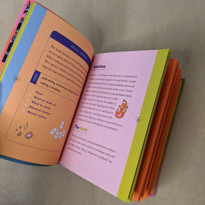 Inside of the guidebook for the Queer Tarot by Ash + Chess. Left page is coral with a light blue edge. Right page is pink with a yellow edge. Both feature black lettering.