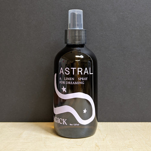 An 8oz dark amber glass bottle with a dropper top that reads: Astral A Linen Spray For Dreaming in light pink text. Sold at Coyote Supply Co a BIPOC and LGBTQIA+ owned zero waste witch store in Reno Nevada
