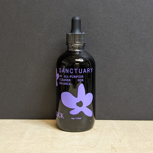 A 4oz dark amber glass bottle with a dropper top that reads: Sanctuary An All-purpose Cleaner For Balance in purple text. . Sold at Coyote Supply Co a BIPOC and LGBTQIA+ owned zero waste witch store in Reno Nevada