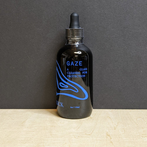 A 4oz dark amber glass bottle with a dropper top that reads: Gaze A Glass Cleaner For Protection in blue text. Sold at Coyote Supply Co a BIPOC and LGBTQIA+ owned zero waste witch store in Reno Nevada
