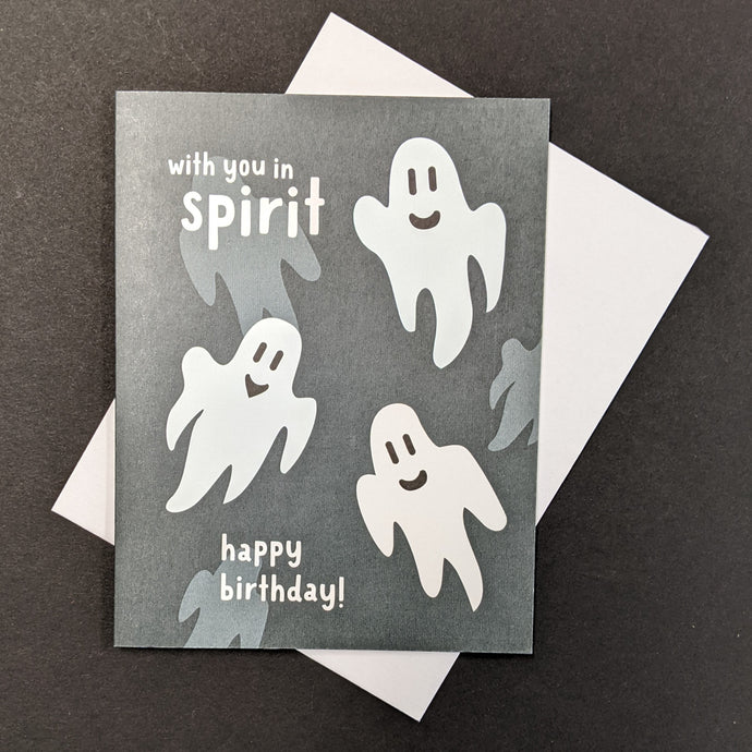 A black birthday card with illustrations of friendly ghosts that reads With you in spirit Happy Birthday!  Sold at Coyote Supply Co a BIPOC and LGBTQIA+ owned zero waste witch store in Reno Nevada 