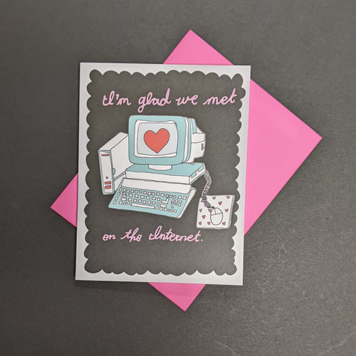 A black greeting card with a white frame and an old school computer with a heart on screen. Around the computer is pink cursive text that reads: I'm glad we met on the Internet.  Sold at Coyote Supply Co a BIPOC and LGBTQIA+ owned zero waste witch store in Reno Nevada 